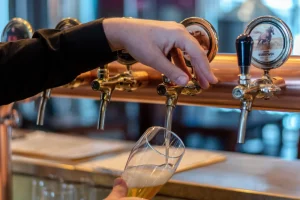 Barman precyzyjnie nalewający piwo rzemieślnicze z mosiężnego kranu