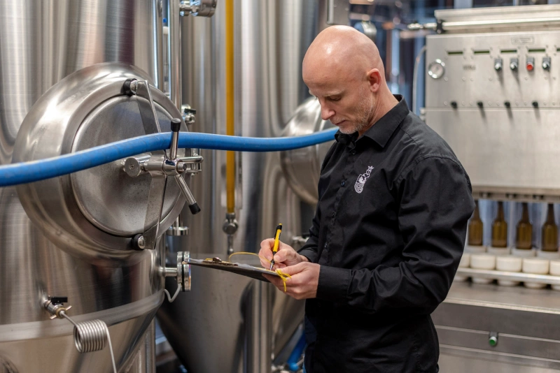 pracownik przeprowadzający kontrolę jakości przy zbiorniku z piwem
